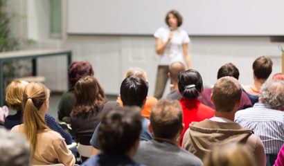 A woman speaker gives a presentation in a lecture hall at a university.