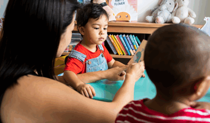 A woman teaches a young child to read.